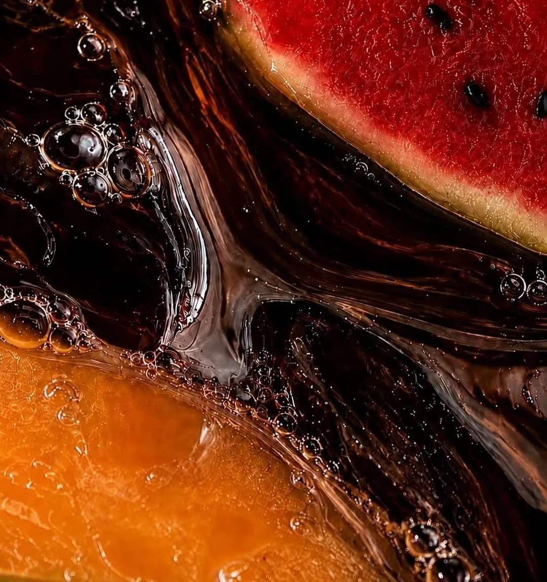 Close-up of coffee swirling between slices of cantaloupe and watermelon