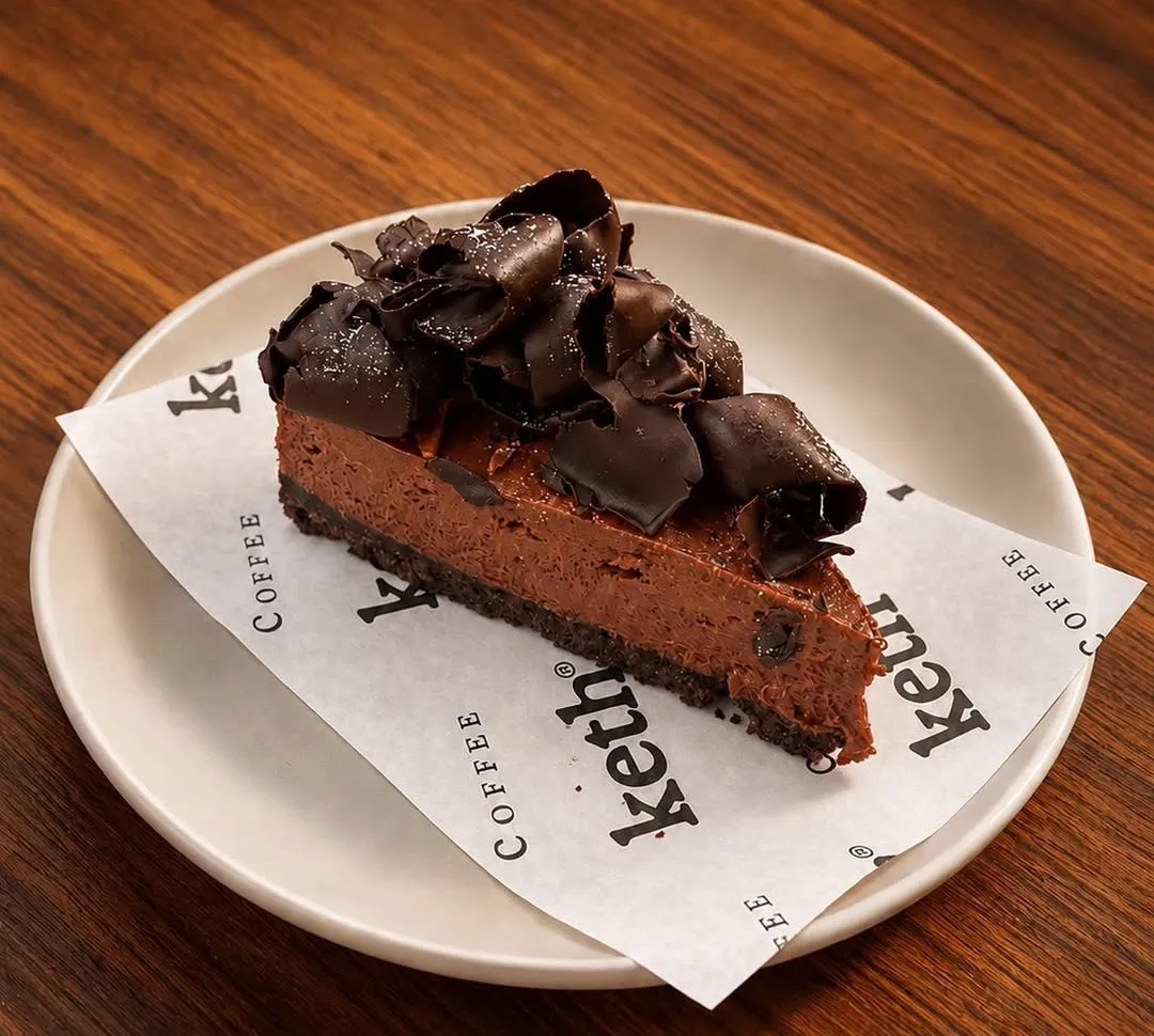 A slice of chocolate mousse cake topped with chocolate curls