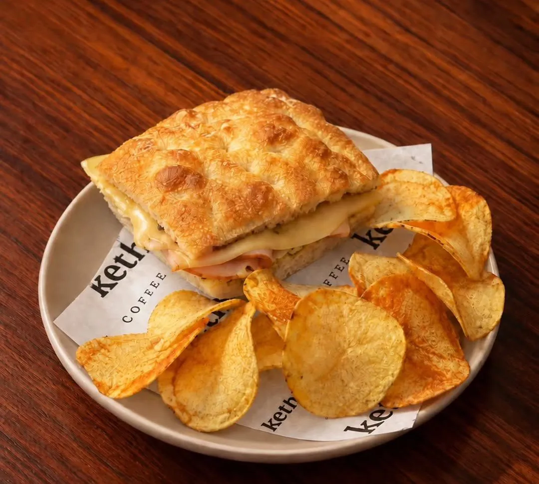 Turkey focaccia with melted cheese and a side of crisps on Keth paper