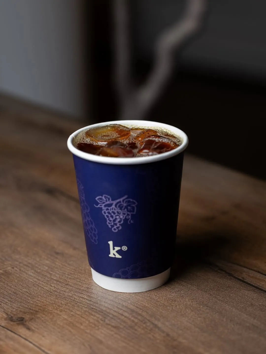 Iced coffee in a navy Keth Grape Tale cup on a wooden table